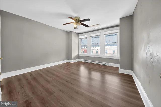 a view of empty room with wooden floor and fan