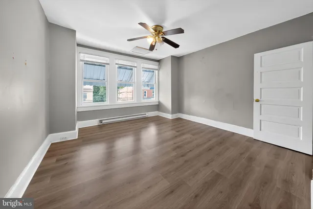 an empty room with wooden floor and windows