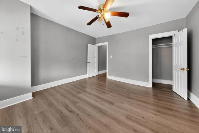 an empty room with wooden floor ceiling fan and window