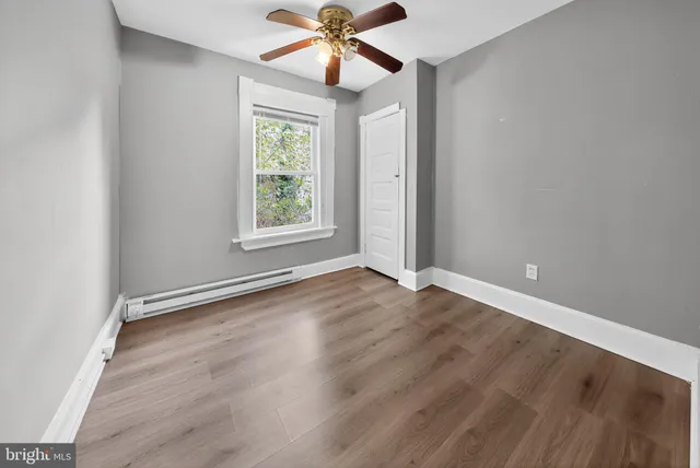 an empty room with wooden floor fan and windows