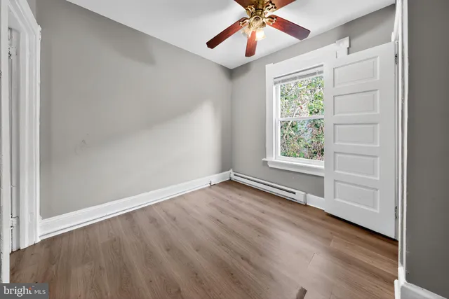 an empty room with wooden floor chandelier fan and windows