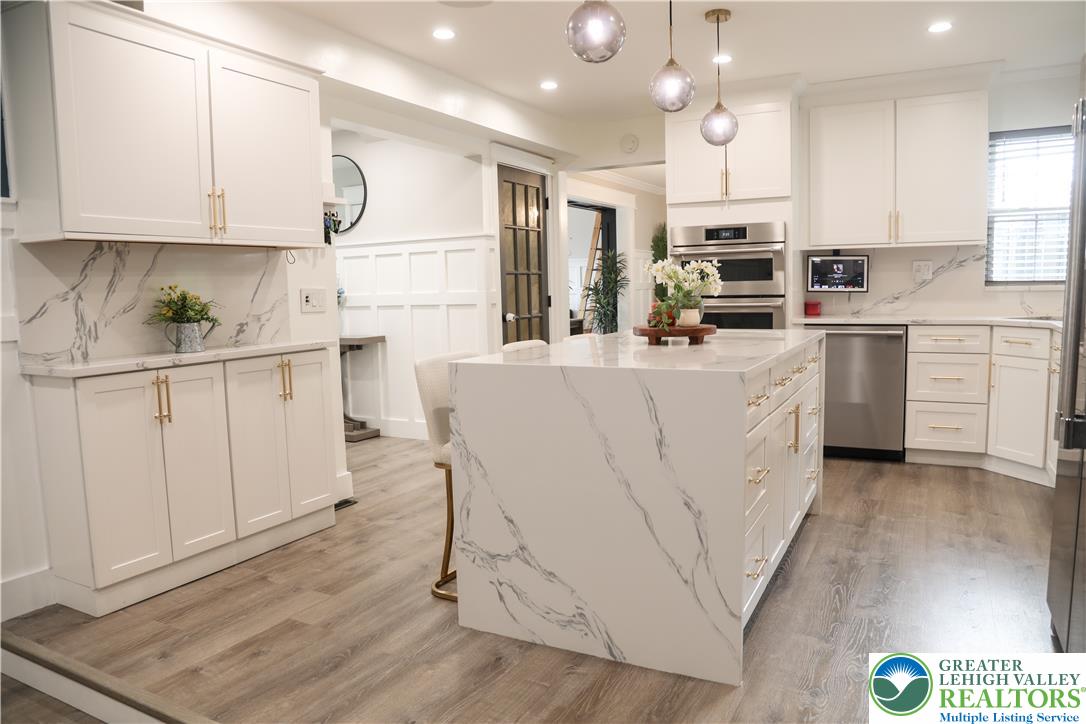 1412 Stanford Road Bethlehem, PA 18018 - Photo 20 of 58 A pristine white kitchen features a waterfall island, sleek stainless steel appliances, and elegant marble-patterned countertops.