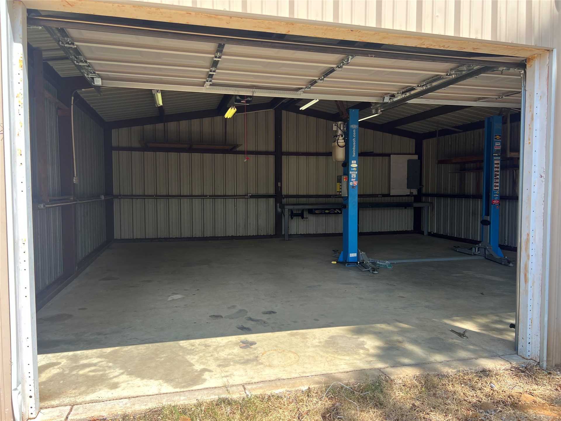 903 South 3rd Street Calera, OK 74730 - Photo 4 of 5 Metal-sided utility building with a roll-up door, concrete flooring, exposed structural beams, and integrated lighting