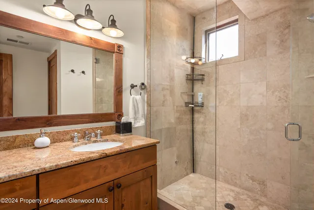 a bathroom with a granite countertop sink a mirror and shower