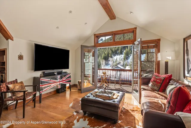 a living room with furniture a flat screen tv and floor to ceiling window