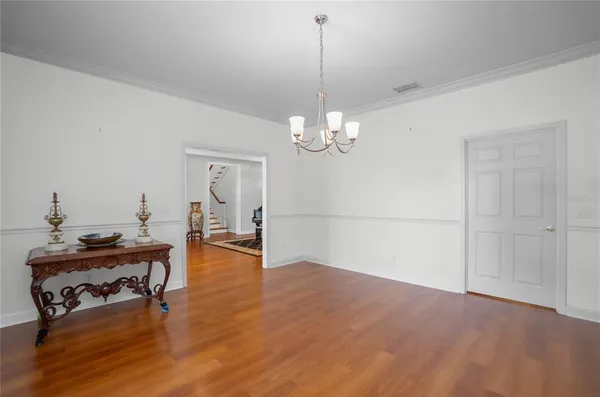 a dining room with furniture a chandelier and wooden floor