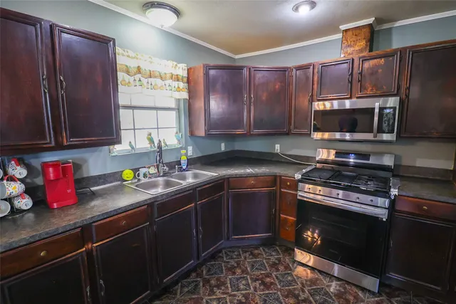 a kitchen with granite countertop wooden cabinets stainless steel appliances and a window