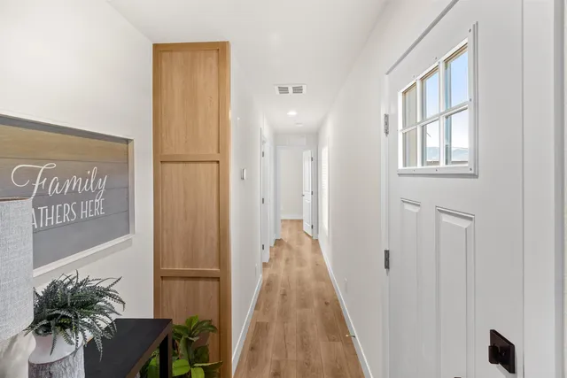 a view of a hallway with wooden floor and a potted plant
