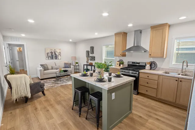 a kitchen with stainless steel appliances a sink a stove a refrigerator cabinets and living room view