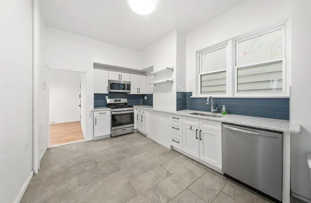 a kitchen with granite countertop white cabinets and stainless steel appliances