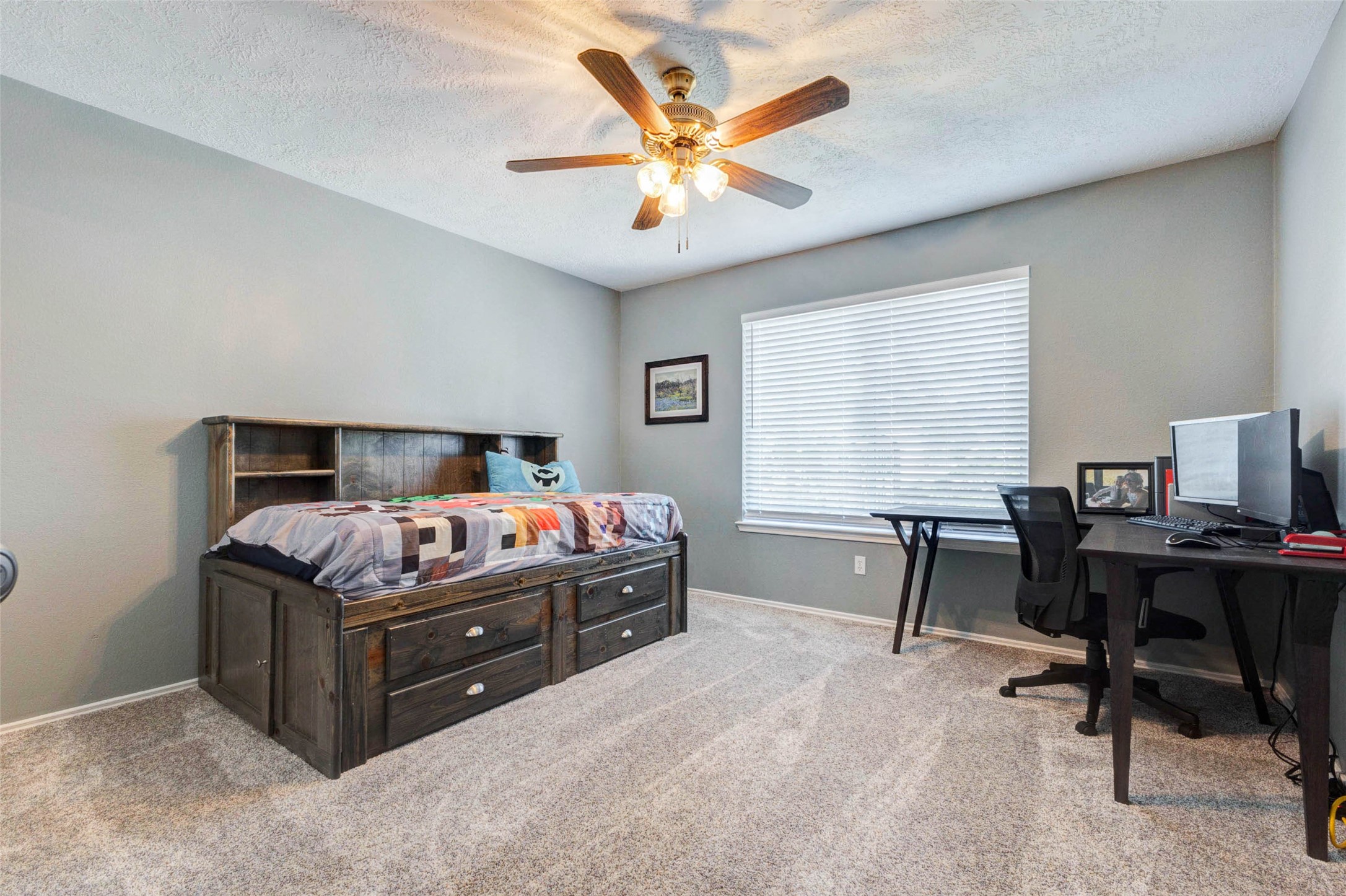 9215 Landry Boulevard Spring, TX 77379 - Photo 31 of 42 Guest bedroom two features plush carpet, neutral paint, a ceiling fan, and a large window that brightens the space with natural light while offering flexibility for guests, a home office, or additional living needs.