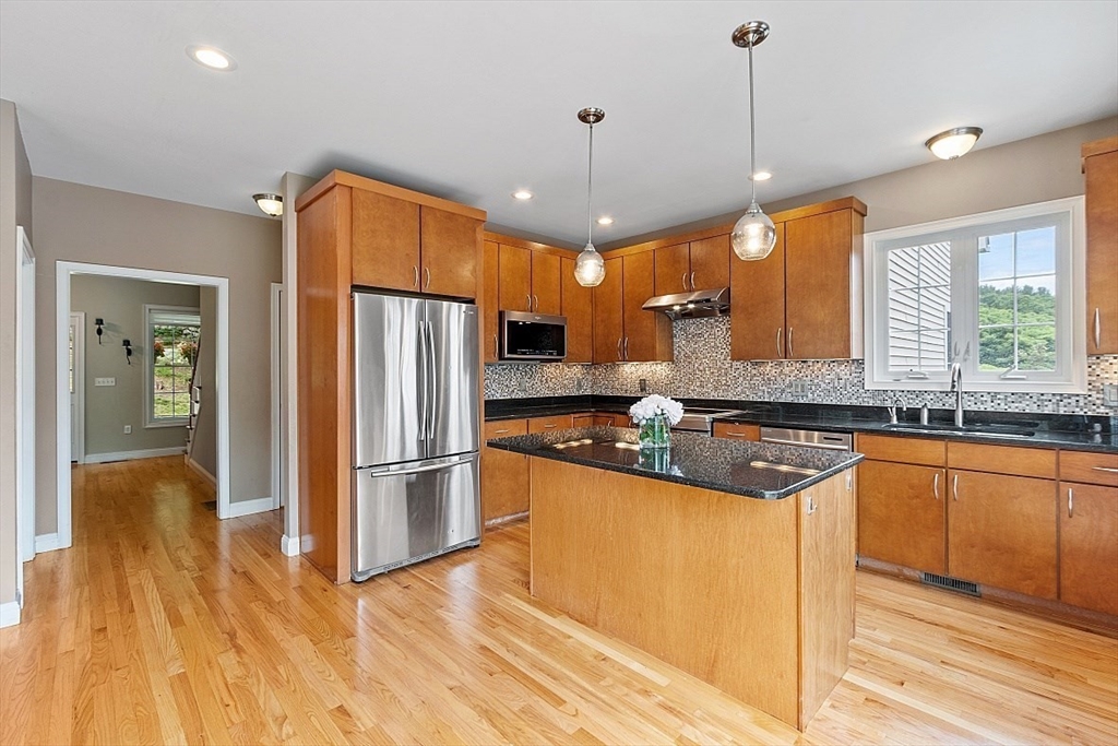 204 Littleton County Road Harvard, MA 01451 - Photo 9 of 42 a kitchen with stainless steel appliances granite countertop a refrigerator a sink dishwasher a stove and a dining table with wooden floor