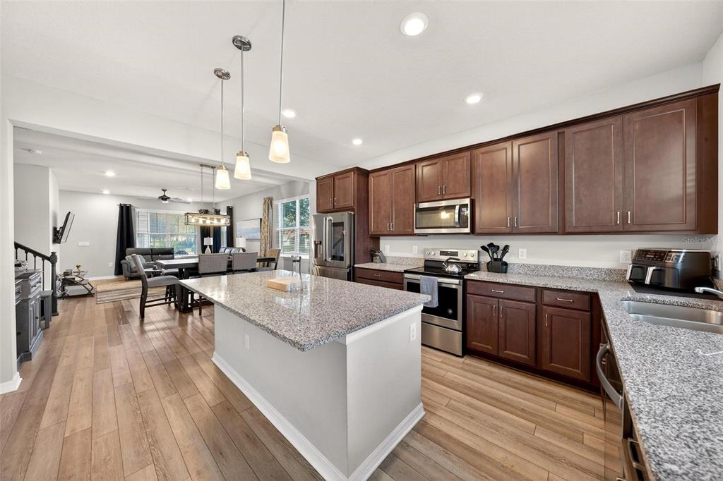 2100 Gopher Tortoise Terrace Oakland, FL 34787 - Photo 14 of 58 a kitchen with stainless steel appliances granite countertop wooden cabinets a sink dishwasher a stove and a refrigerator with wooden floor