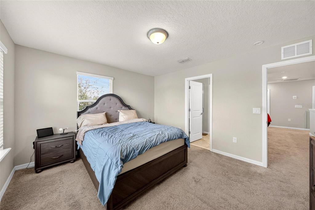 2100 Gopher Tortoise Terrace Oakland, FL 34787 - Photo 30 of 58 a spacious bedroom with a bed and a lamp on dresser