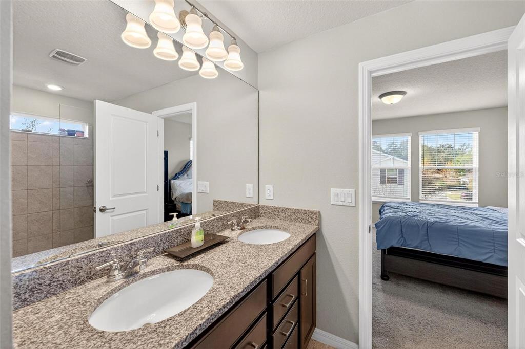 2100 Gopher Tortoise Terrace Oakland, FL 34787 - Photo 35 of 58 a en suite bathroom with a granite countertop sink a mirror and a shower