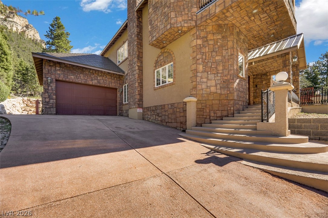 264 Crestview Drive Mount Charleston, NV 89124 - Photo 7 of 78 This home features a stone and stucco exterior with a garage and a grand staircase leading to the entrance.