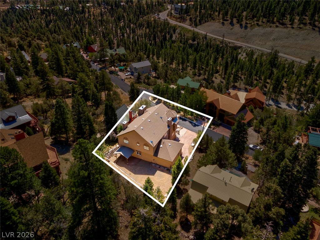 264 Crestview Drive Mount Charleston, NV 89124 - Photo 73 of 78 An aerial view captures a spacious home nestled among a lush, treed landscape with a nearby road.