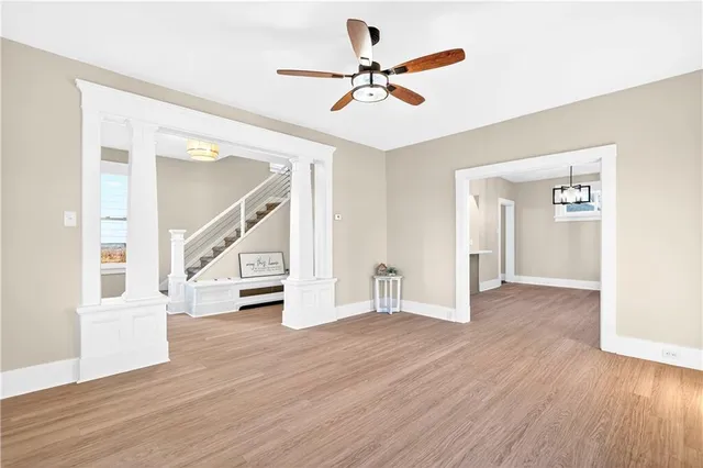 a view of an empty room with wooden floor and a ceiling fan