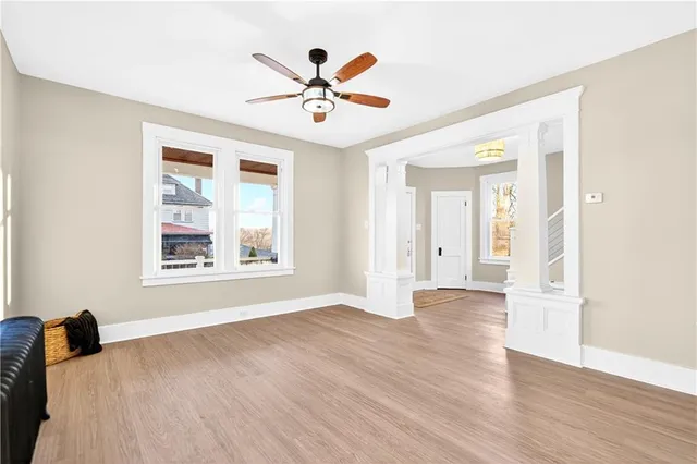 a view of empty room with wooden floor and fan