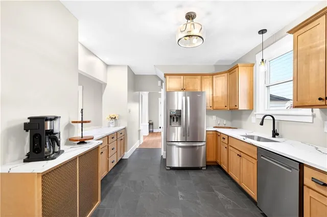 a kitchen with stainless steel appliances a sink a stove a refrigerator cabinets and a window