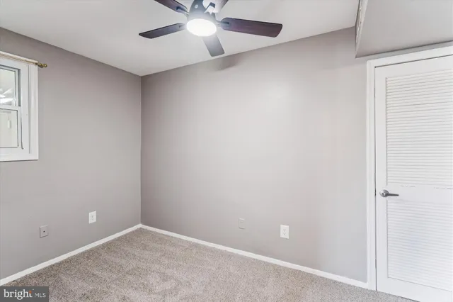 an empty room with a window and a fan
