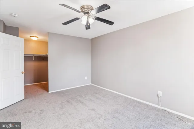 an empty room with a chandelier fan and closet