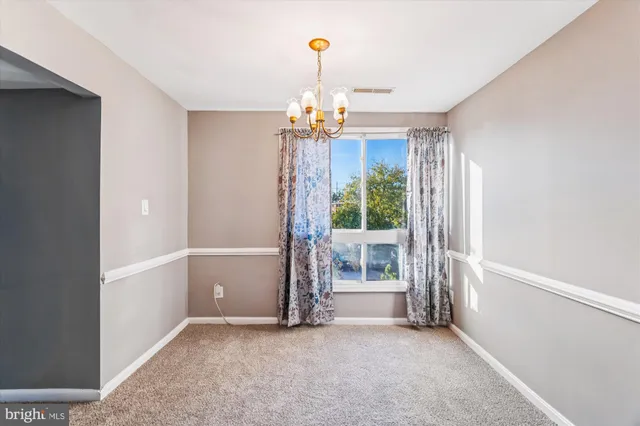 an empty room with chandelier fan and windows