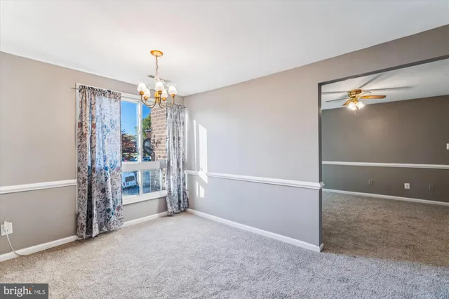 an empty room with chandelier fan and entrance