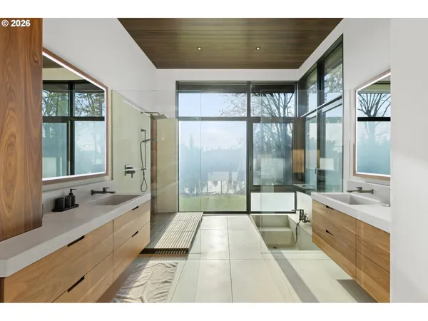 a bathroom with a double vanity sink a large mirror and a bathtub