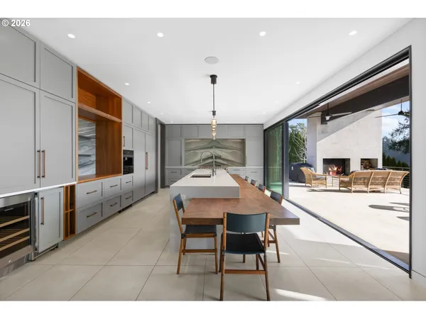 a dining hall with stainless steel appliances kitchen island granite countertop a table chairs and a refrigerator