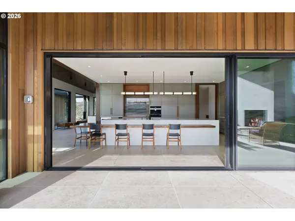 a living room with stainless steel appliances furniture a rug and a kitchen view
