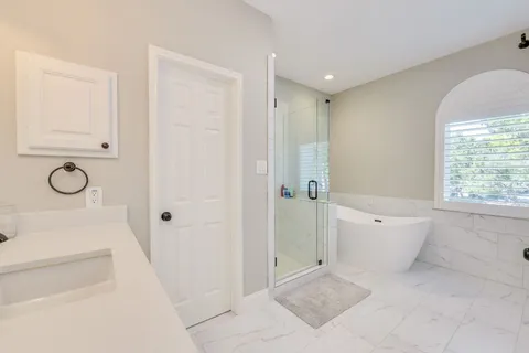 a bathroom with a tub shower and mirror