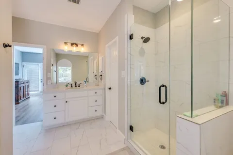 a bathroom with a double vanity sink mirror and shower
