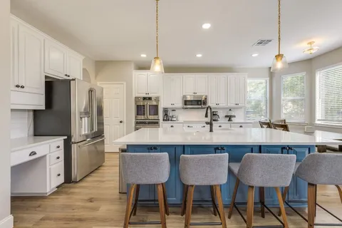 a kitchen with stainless steel appliances a dining table chairs microwave and cabinets