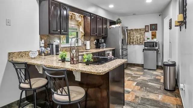a kitchen with granite countertop kitchen island stainless steel appliances a table and chairs