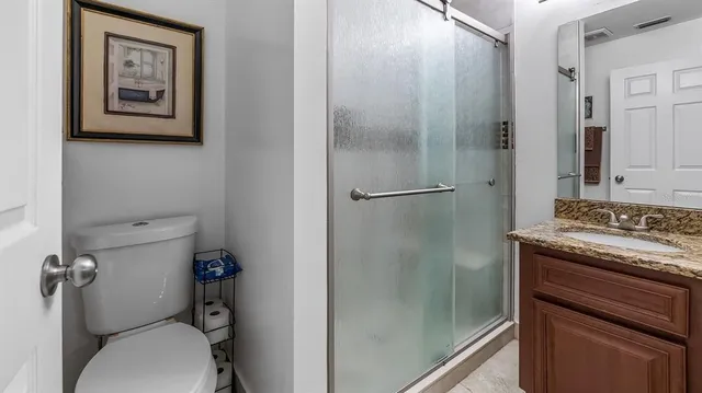 a bathroom with a granite countertop toilet and a sink