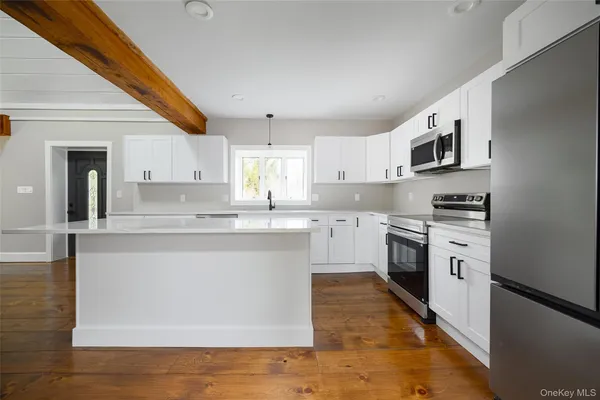 a hallway with white cabinets and wooden floor
