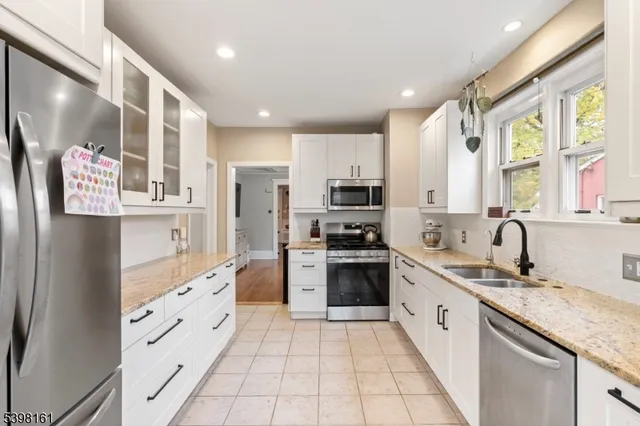 a large kitchen with stainless steel appliances granite countertop a refrigerator and a sink
