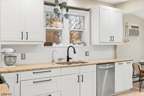 a kitchen with white cabinets and a window