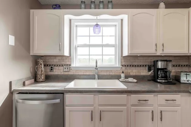a kitchen with granite countertop a sink and a white cabinets