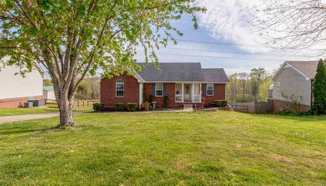 a front view of a house with a garden and tree