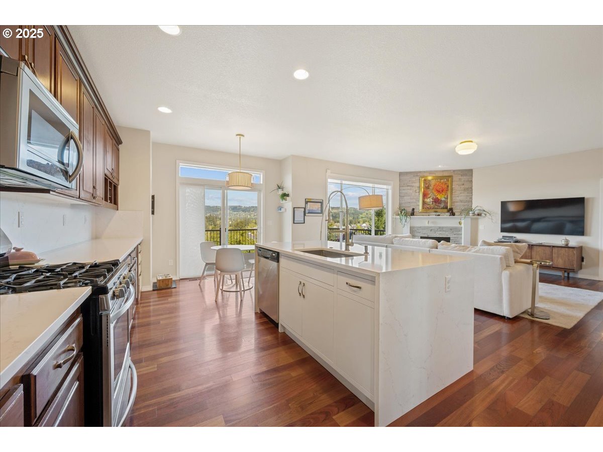 5254 Wedgewood Loop Newberg, OR 97132 - Photo 15 of 43 a open kitchen with stainless steel appliances kitchen island granite countertop a stove a sink a refrigerator and white cabinets with wooden floor