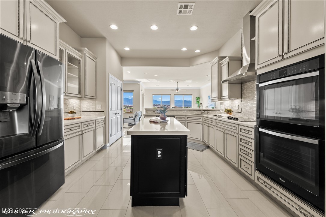 1348 Basin View Mesquite, NV 89034 - Photo 14 of 70 Kitchen with stainless steel fridge, tasteful backsplash, a center island, recessed lighting, and glass insert cabinets