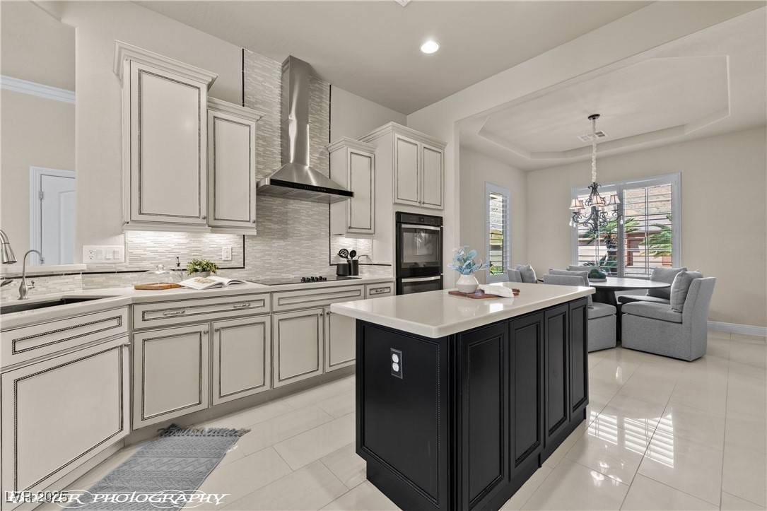 1348 Basin View Mesquite, NV 89034 - Photo 15 of 70 Kitchen with dark cabinetry, a kitchen island, decorative backsplash, wall chimney exhaust hood, and decorative light fixtures