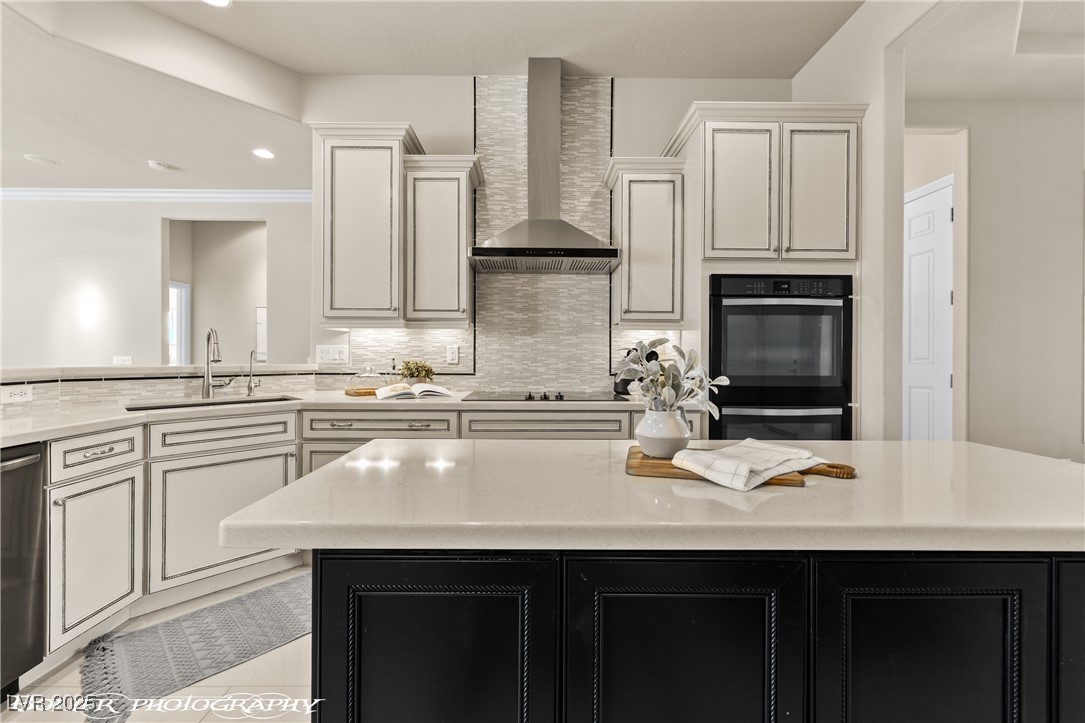 1348 Basin View Mesquite, NV 89034 - Photo 16 of 70 Kitchen featuring dark cabinets, decorative backsplash, wall chimney exhaust hood, light stone counters, and recessed lighting