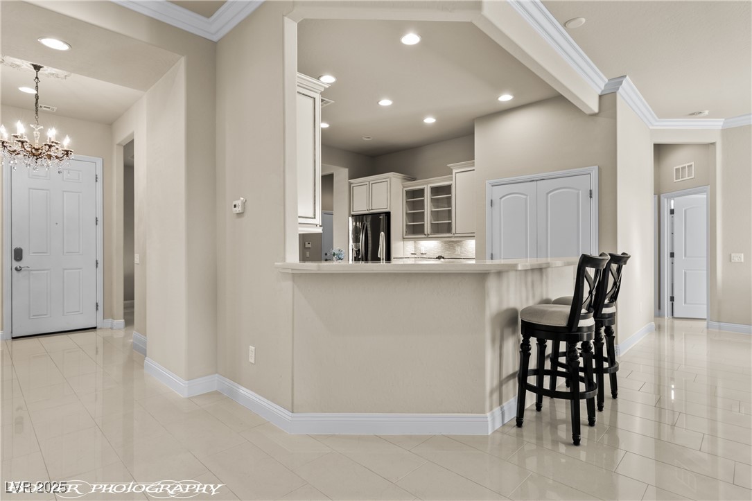 1348 Basin View Mesquite, NV 89034 - Photo 29 of 70 Kitchen with glass insert cabinets, crown molding, a kitchen bar, white cabinets, and backsplash