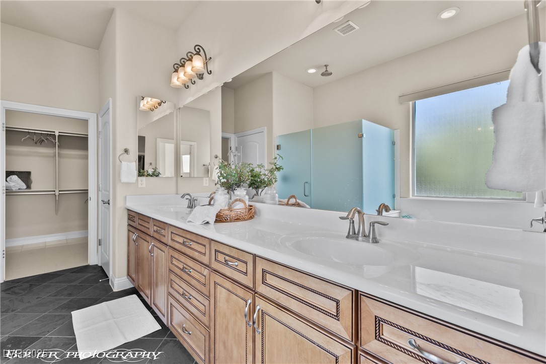 1348 Basin View Mesquite, NV 89034 - Photo 39 of 70 Bathroom with double vanity, dark tile patterned flooring, a walk in closet, and a shower stall