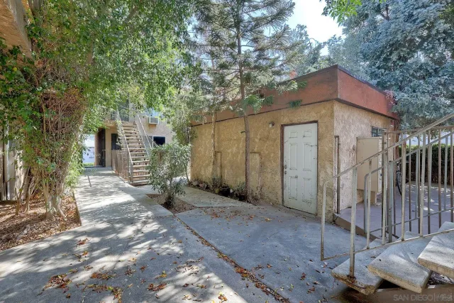 a view of a house with large trees and a small yard