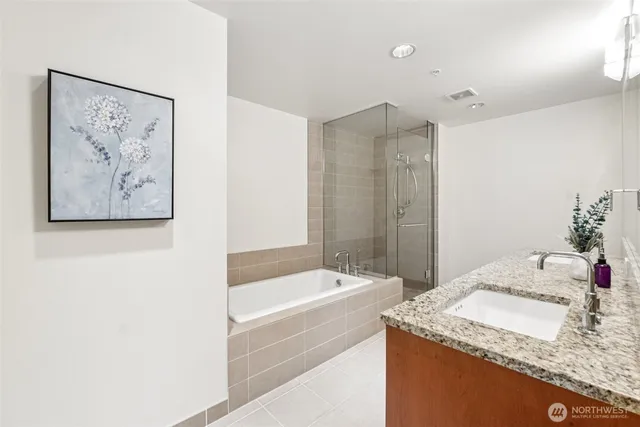 a bathroom with a granite countertop sink a bathtub and a shower