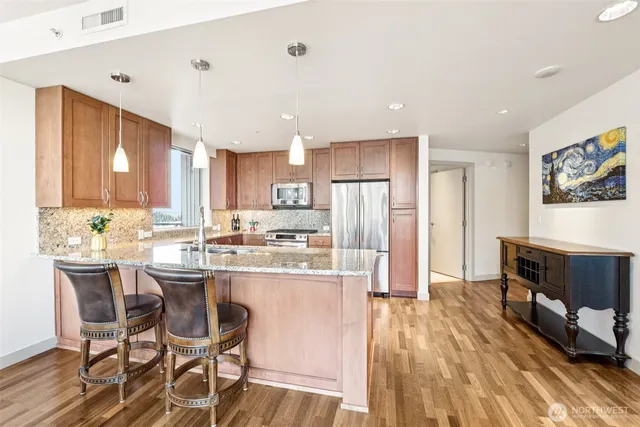 a kitchen with stainless steel appliances a dining table chairs and wooden floor